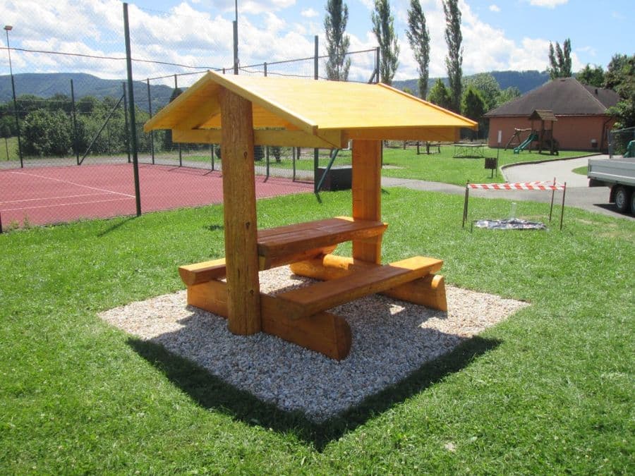 Zastřešené dřevěné posezení s lavicemi na kamenné dlažbě